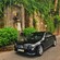 A Mercedes Benz sedan drives past the bust of Carlos Franca